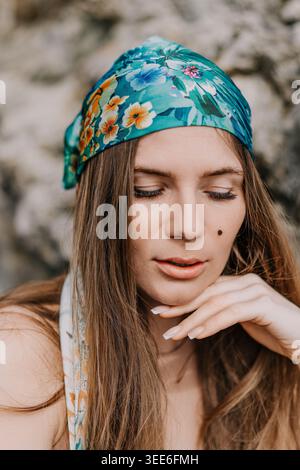 Donna con foulard ritratto bella giovane donna a occhi chiusi che indossa bandana floreale su sfondo roccioso sfocato Foto Stock