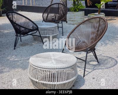 Tranquillo e rilassante patio all'aperto con moderna sedia in tessuto e mobili da tavolo in vimini su terreno di ghiaia ambiente tranquillo salotto in giardino per l'estate Foto Stock