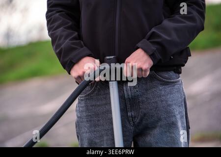 Sezione centrale di una persona che gonfia l'attrezzatura con una pompa a mano all'aperto Foto Stock