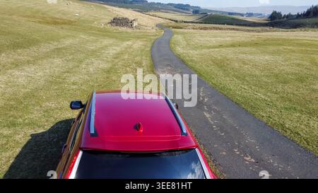 Vista aerea di un'auto rossa su una tortuosa brughiera che si estende nel paesaggio di Wensleydale Foto Stock