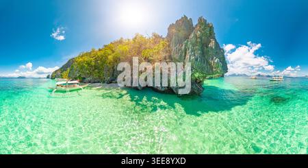 360 veduta della spiaggia di sabbia bianca di Entalula, El Nido, Palawan con palme ondeggianti, acqua turchese, tradizionali barche bangka e spettacolari formazioni carsiche di pietra calcarea Foto Stock