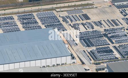 Veduta aerea di BYD AUTO THAILAND CO. LTD Fabbrica con migliaia di nuovi veicoli elettrici parcheggiati in file ordinate accanto ai grandi magazzini industriali di P. Foto Stock