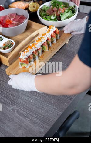 Vista di un dipendente di un ristorante giapponese che prepara un piatto di sushi. Foto Stock
