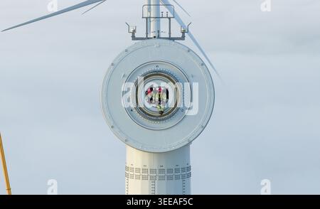 Paesi Bassi - 26 novembre 2025: Veduta aerea di due tecnici con equipaggiamento ad alta visibilità e caschi rossi seduti all'interno del centro circolare di un grande vento Foto Stock