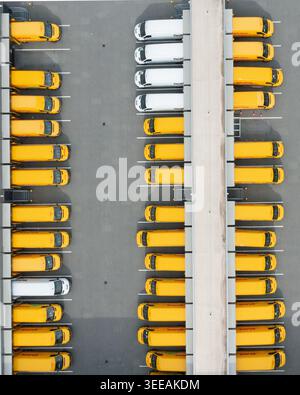 01 settembre 2019: Vista aerea di file di furgoni gialli e bianchi parcheggiati in una zona di carico del centro di distribuzione logistica. Foto Stock