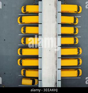01 settembre 2019: Veduta aerea dei furgoni DHL gialli parcheggiati presso una banchina di carico di un centro di distribuzione con piattaforme in asfalto grigio e cemento. Foto Stock