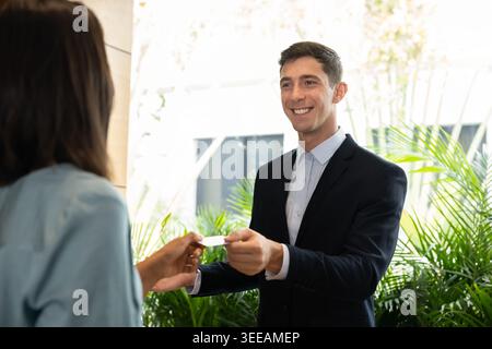 La receptionist sorridente consegna la chiave a una donna ospite dell'hotel Foto Stock