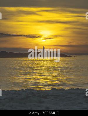 Spettacolare tramonto dorato sul mare calmo con il faro sagomato di Gimsoya e una piccola isola nelle isole Lofoten, Norvegia settentrionale, fotografata in estate. Foto Stock