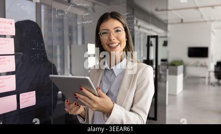 Ritratto di una donna d'affari che tiene un tablet digitale e guarda la fotocamera Foto Stock