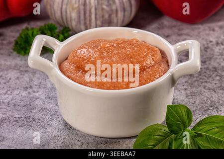 Primo piano di uova di pesce rosa, note anche come taramosalata, servite in una ciotola di ceramica bianca. Ingredienti freschi come aglio, basilico e peperoni Foto Stock