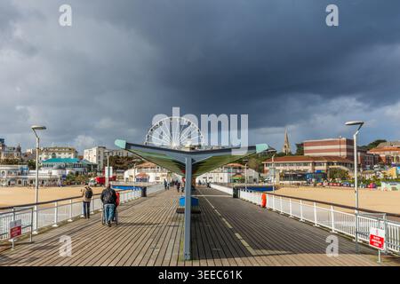 Bournemouth, Regno Unito - 25 marzo 2026: Nuvole scure sopra le persone sulla passeggiata del molo di Bournemouth. Foto Stock