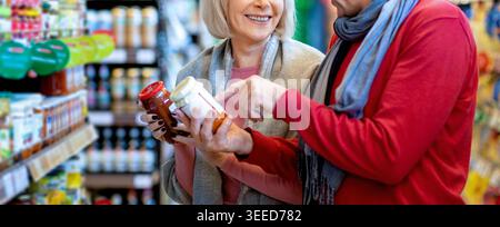 Le donne stanno facendo acquisti insieme in un negozio di alimentari e discutono di vari prodotti Foto Stock