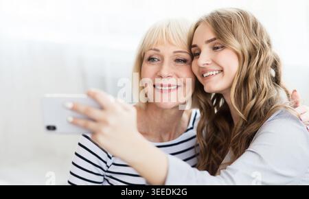 Affascinante blogger che scatta selfie con la mamma sullo smartphone Foto Stock