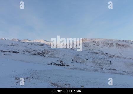 Ampio paesaggio invernale della valle di Chunkurchak, con colline innevate e creste di montagna sotto un cielo azzurro limpido, paesaggi naturali tranquilli in Kirghizistan, Foto Stock
