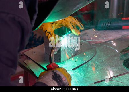 Processo di saldatura mig dell'alluminio con scintille brillanti in un'officina di metallo. Foto Stock