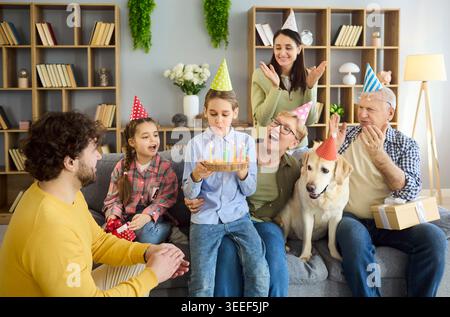 Buona festa di compleanno multigenerazionale in famiglia a casa con torta, candele e cane Foto Stock
