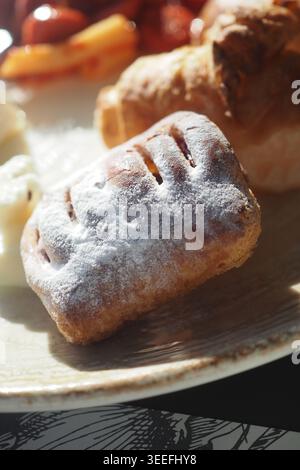 Pasticceria appena sfornata su un piatto con altri alimenti Foto Stock