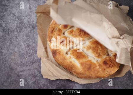 Pane fresco posto su carta marrone su un bancone della cucina Foto Stock