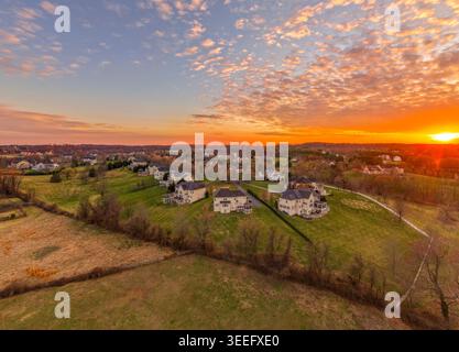 Una fotografia aerea con drone cattura un'ampia scena pastorale a Clarksville, Howard County, Maryland, con un vivace tramonto arancione. Un piccolo gruppo di l Foto Stock