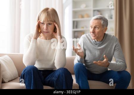 Una donna anziana stressata seduta sul divano durante una discussione con il marito a casa Foto Stock