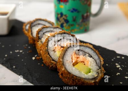 Uno scatto da studio ad alto angolo di cinque pezzi di sushi fritti in casa (involtini tempura) ripieni di salmone fresco e avocado. I rotoli sono disposti in modo diag Foto Stock