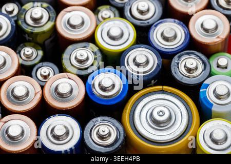 Primo piano delle estremità positive della batteria colorata. Batterie scariche di diverse dimensioni e formati, vista dall'alto, messa a fuoco selettiva. Batteria alcalina usata. Concetto di spazzatura pericolosa Foto Stock