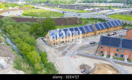 Vista aerea delle moderne case in legno con pannelli solari sui tetti vicino a un'autostrada e alberi verdi a Utrecht, Utrecht, Paesi Bassi. Foto Stock