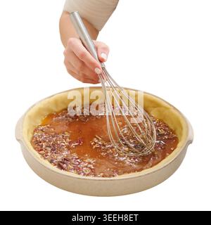 Donna fornaio che utilizza una frusta di filo per mescolare il ripieno di torta pecan nella crosta di impasto. Preparazione professionale di cucina casalinga per dessert natalizi. Processo culinario su di me Foto Stock