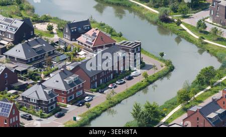 Vista aerea delle moderne case residenziali con tetti scuri e pannelli solari lungo un canale tortuoso di Utrecht, Utrecht, Paesi Bassi. Foto Stock