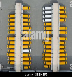 01 settembre 2019: Veduta aerea dei furgoni DHL gialli e bianchi parcheggiati in file simmetriche presso una banchina di carico del centro di distribuzione logistica. Foto Stock