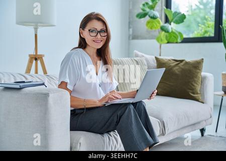 Ritratto di una donna di mezza età con un notebook seduto in pullman Foto Stock