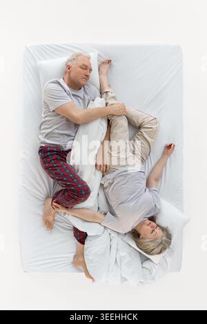 La coppia più anziana si è infilata nella coperta con vista dall'alto del letto bianco. Foto Stock
