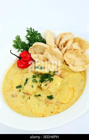 Un curry di pesce di Goan servito con peperoncino rosso, coriandolo e mini papadum. Foto Stock