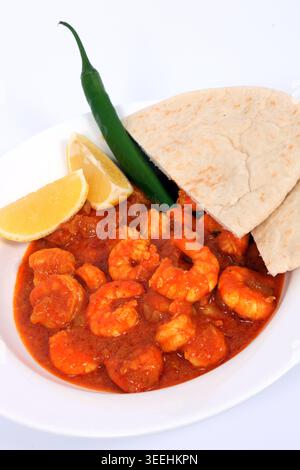 Un curry di pesce di Goan servito con peperoncino rosso, coriandolo e mini papadum. Foto Stock