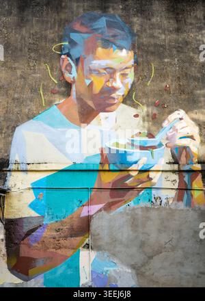 Vivace murale di Street art che raffigura un colorato ritratto stilizzato di una persona che mangia, dipinto su un muro urbano, George Town, Penang, Malesia Foto Stock