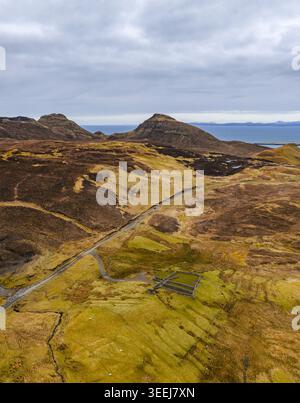 Veduta aerea del Quiraing con l'aspro paesaggio di montagna, la strada tortuosa e le strutture in pietra sotto un cielo nuvoloso Isola di Skye, Scozia, uni Foto Stock