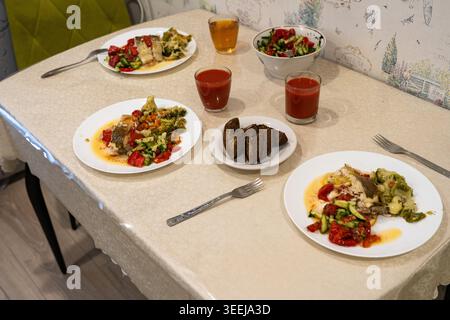 Una variopinta cena con pollo alla griglia, verdure fresche e bevande aromatizzate servite su un tavolo da pranzo ben impostato Foto Stock