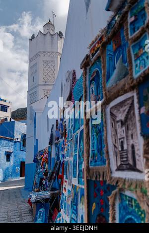 A Chefchaouen, le colorate strade blu sono fiancheggiate da splendide opere d'arte e oggetti artigianali marocchini, sullo sfondo di un Majes Foto Stock