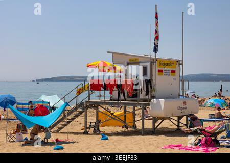 Stazione bagnino della spiaggia di Bournemouth sotto i cieli estivi, stazione di sicurezza RNLI con vista sulla trafficata costa. Foto Stock