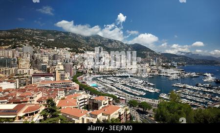 Vista panoramica del porto turistico di Port Hercule a Monaco, con yacht, barche e il Mar Mediterraneo circondati dalla città e dalle montagne costiere Foto Stock