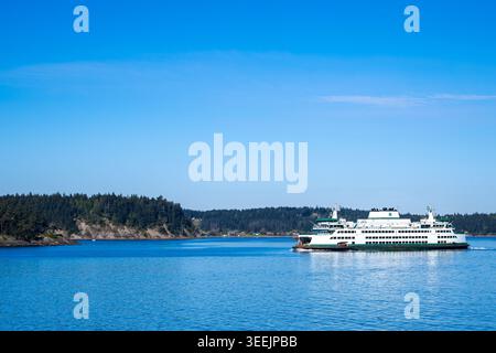 Un traghetto dello stato di Washington attraversa le calme acque blu di Puget Sound, circondato dal paesaggio del Pacifico nord-occidentale. Foto Stock