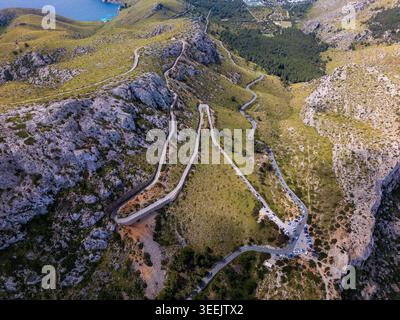 Vista aerea delle tortuose strade di montagna di Cap de Formentor, circondate da scogliere rocciose e da una lussureggiante vegetazione verde nelle Isole Baleari, in Spagna. Foto Stock