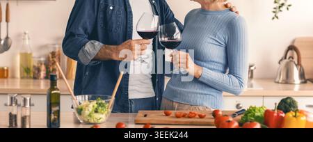La coppia ama cucinare insieme in cucina mentre condivide un toast con del vino Foto Stock