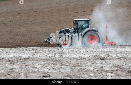 Claas Axion 830 eruttante di potenza in calce appena sparsa su un campo arato. Il calcare in polvere aiuta la fertilità del terreno. Cumbria, Regno Unito. Foto Stock