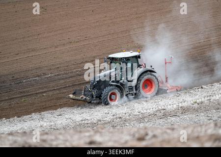 Claas Axion 830 eruttante di potenza in calce appena sparsa su un campo arato. Il calcare in polvere aiuta la fertilità del terreno. Cumbria, Regno Unito. Foto Stock