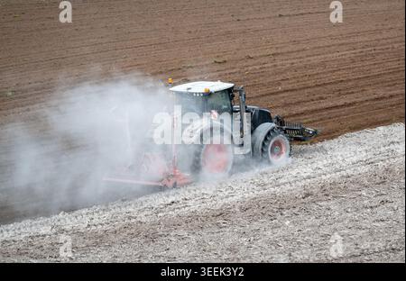 Claas Axion 830 eruttante di potenza in calce appena sparsa su un campo arato. Il calcare in polvere aiuta la fertilità del terreno. Cumbria, Regno Unito. Foto Stock