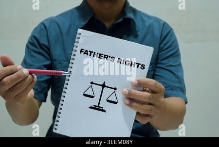 Un uomo d'affari ha in mano un libro con il nome dei diritti del padre. Foto Stock