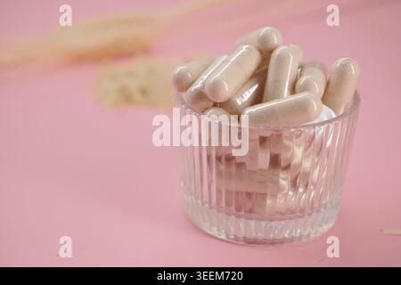 Capsule bianche in vetro trasparente su una superficie rosa Foto Stock