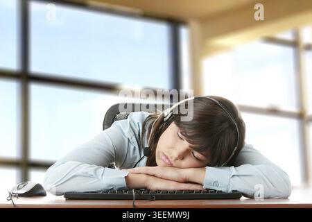 Giovane donna caucasica dormire sulla tastiera Foto Stock