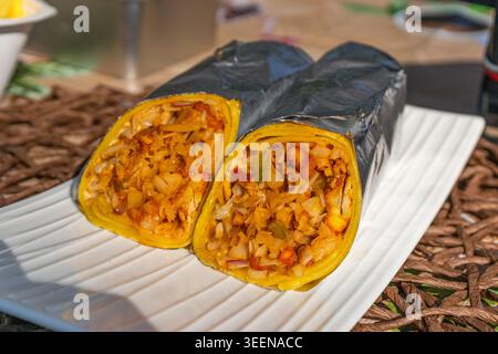 Primo piano di un burrito tagliato a metà, riempito con un mix di verdure e spezie. Burrito messicano, cibo messo su un piatto bianco Foto Stock